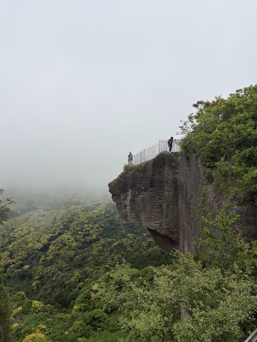 鋸山の地獄のぞき、岩の突端に人が立つ景色を遠景から