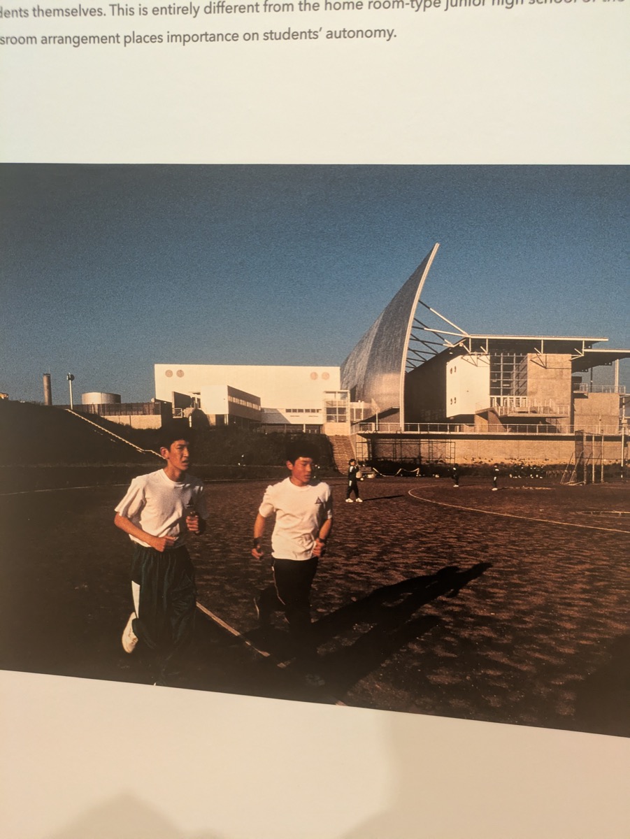 山本理顕展で展示されていた水辺の建築写真。人が建物の近くに立っている