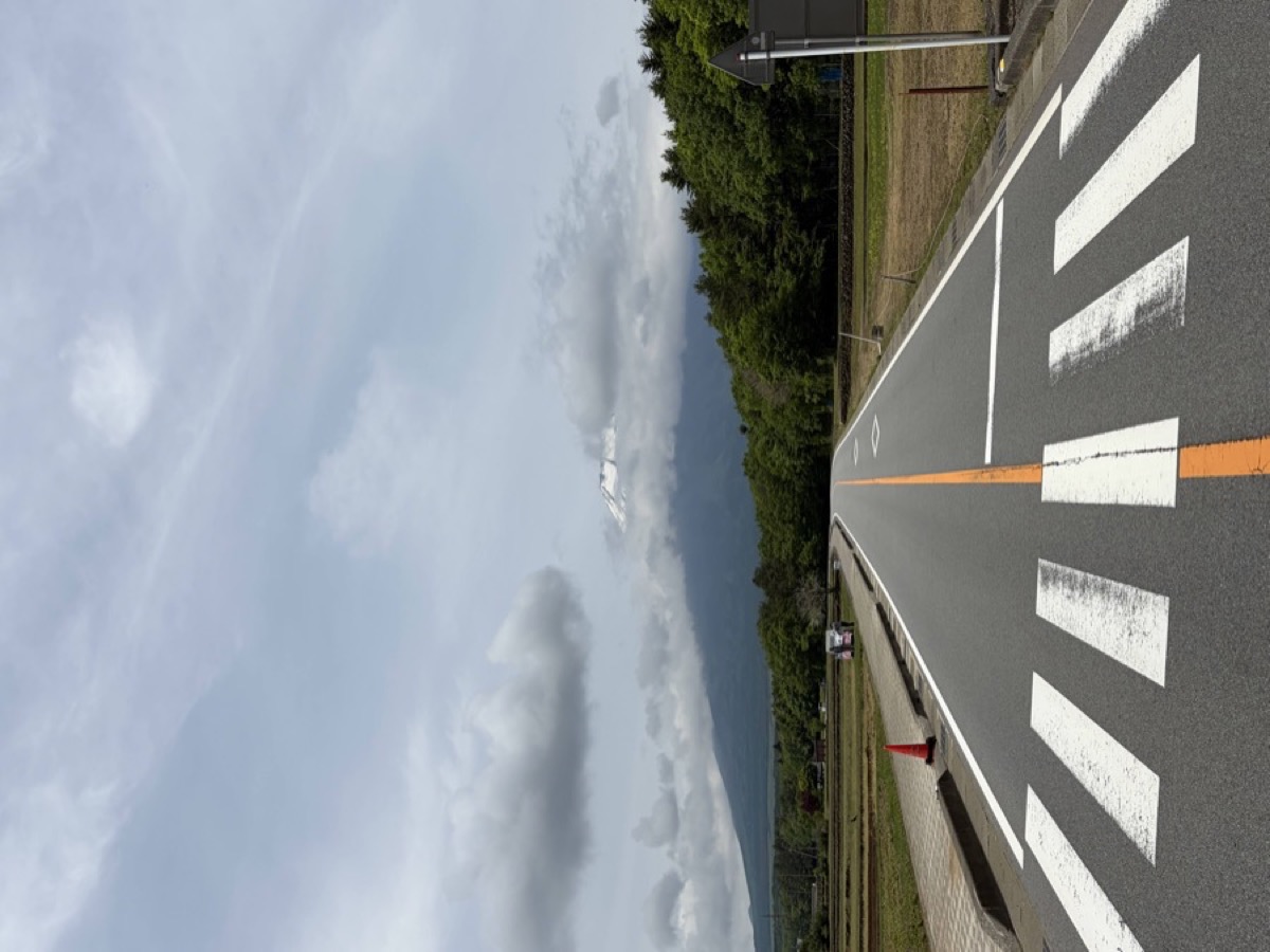 道路の正面奥に富士山が見える。横断歩道の手前から撮影した山中湖近くの景色
