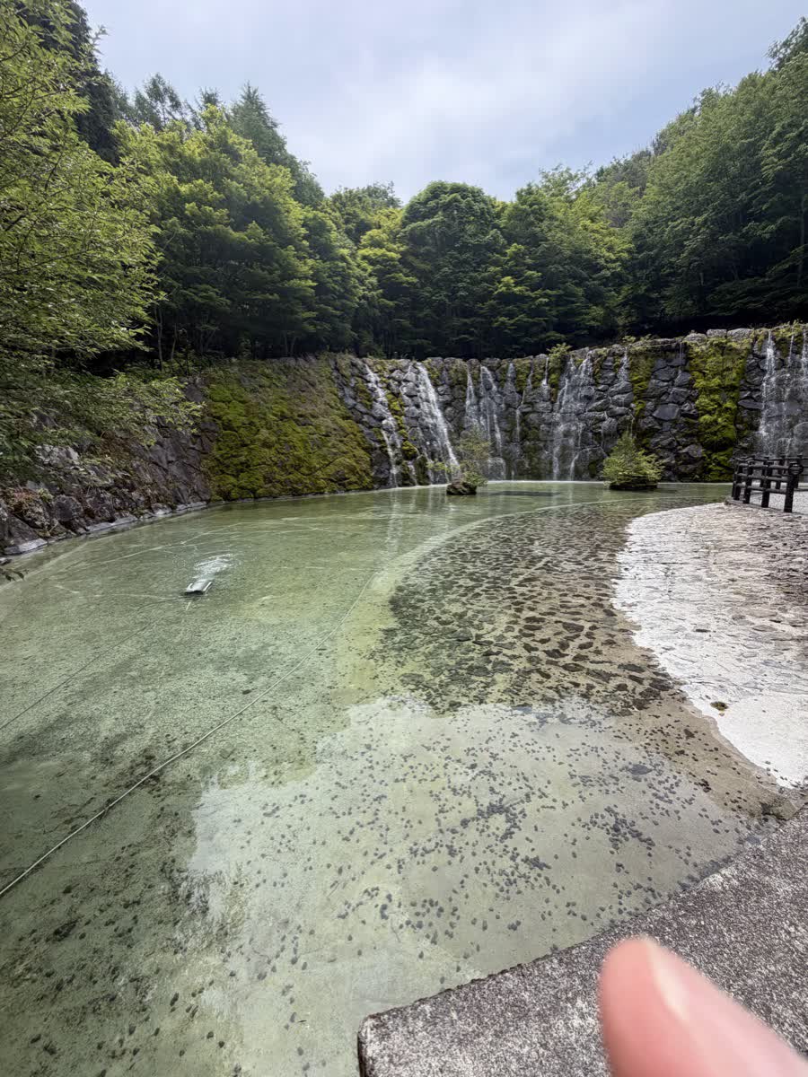 明神の滝の全景。幅広い岩壁から複数の流れが落ち、底に緑色の池が広がっている