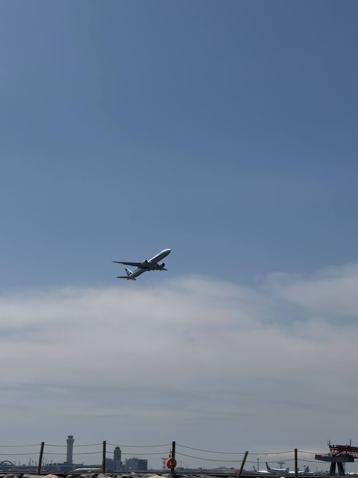 城南島海浜公園の海越しに飛ぶ旅客機と羽田空港の管制塔