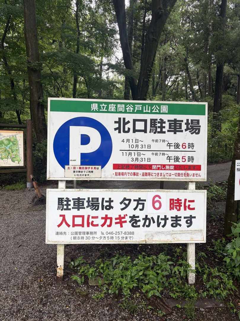 県立座間谷戸山公園・北口駐車場の看板。4月1日から10月31日は午後6時、11月1日から3月31日は午後5時に閉門し施錠すると書かれている