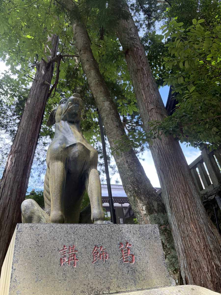 三峯神社の杉木立の中に立つオオカミの石像