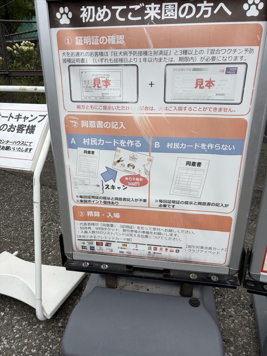 わんダフルネイチャーヴィレッジ入口の案内看板。狂犬病予防接種注射済証と混合ワクチン証明書の見本が掲示されている