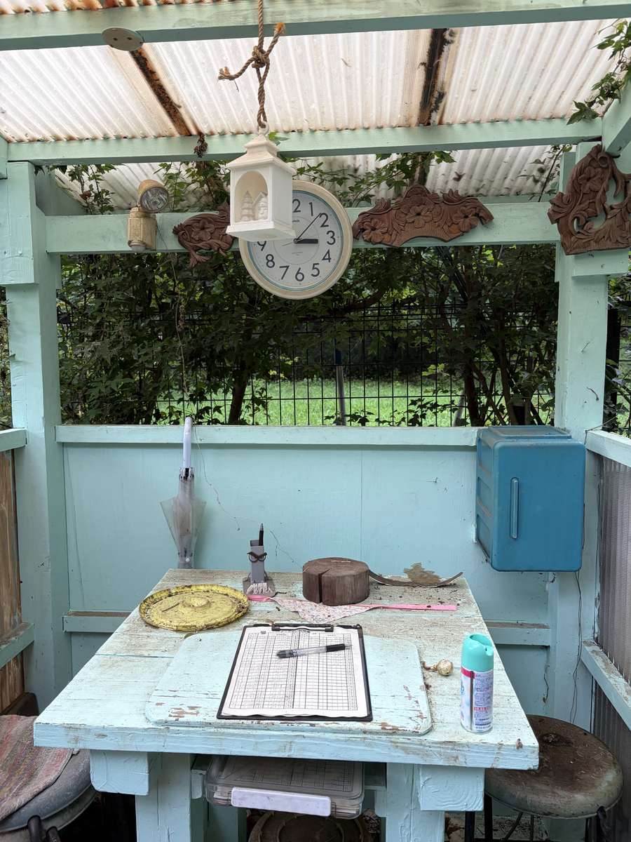 水色に塗られた木の小屋。机の上に利用簿と時計、スプレー缶が置かれている