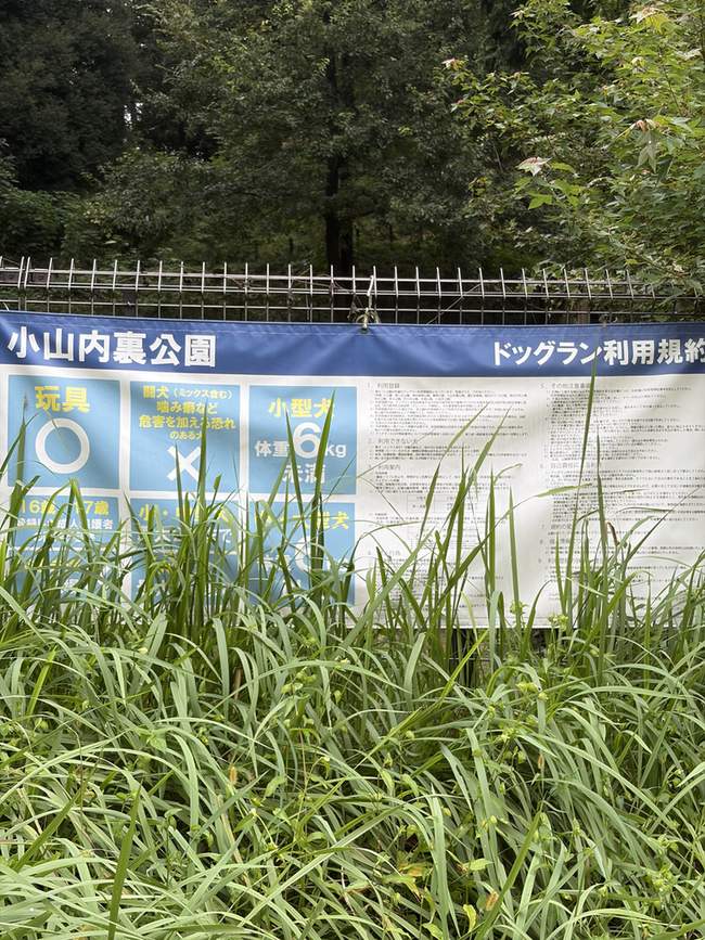 フェンスに掛かった小山内裏公園ドッグラン利用規約の横断幕。玩具は○、闘犬は×、小型犬は体重6kg未満と書かれている