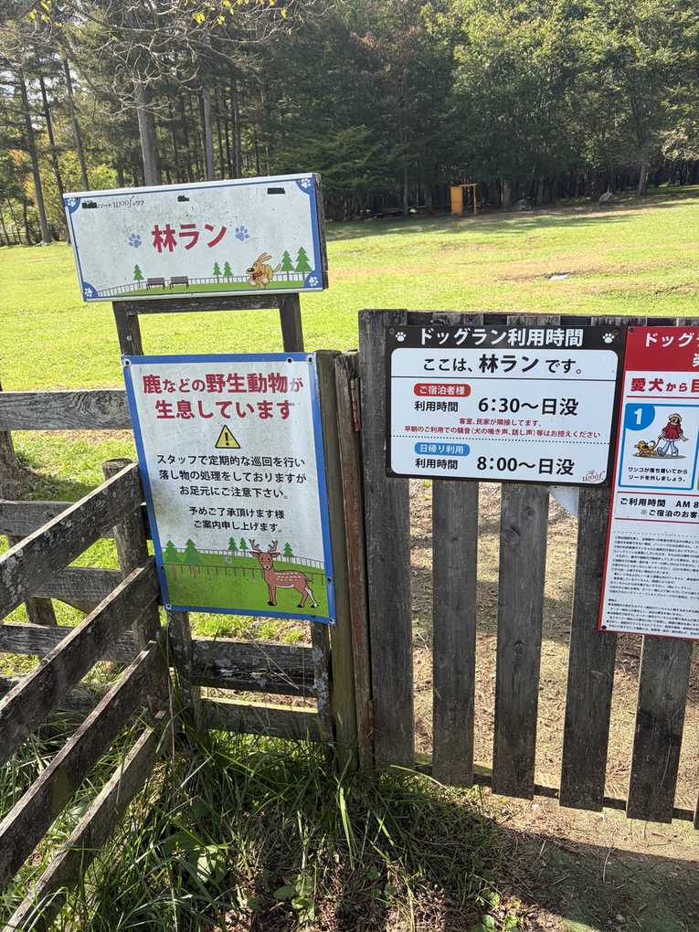 林ランの入口の看板。「鹿などの野生動物が生息しています」の注意書きと、ドッグラン利用時間(宿泊者6:30〜日没、日帰り8:00〜日没)の掲示